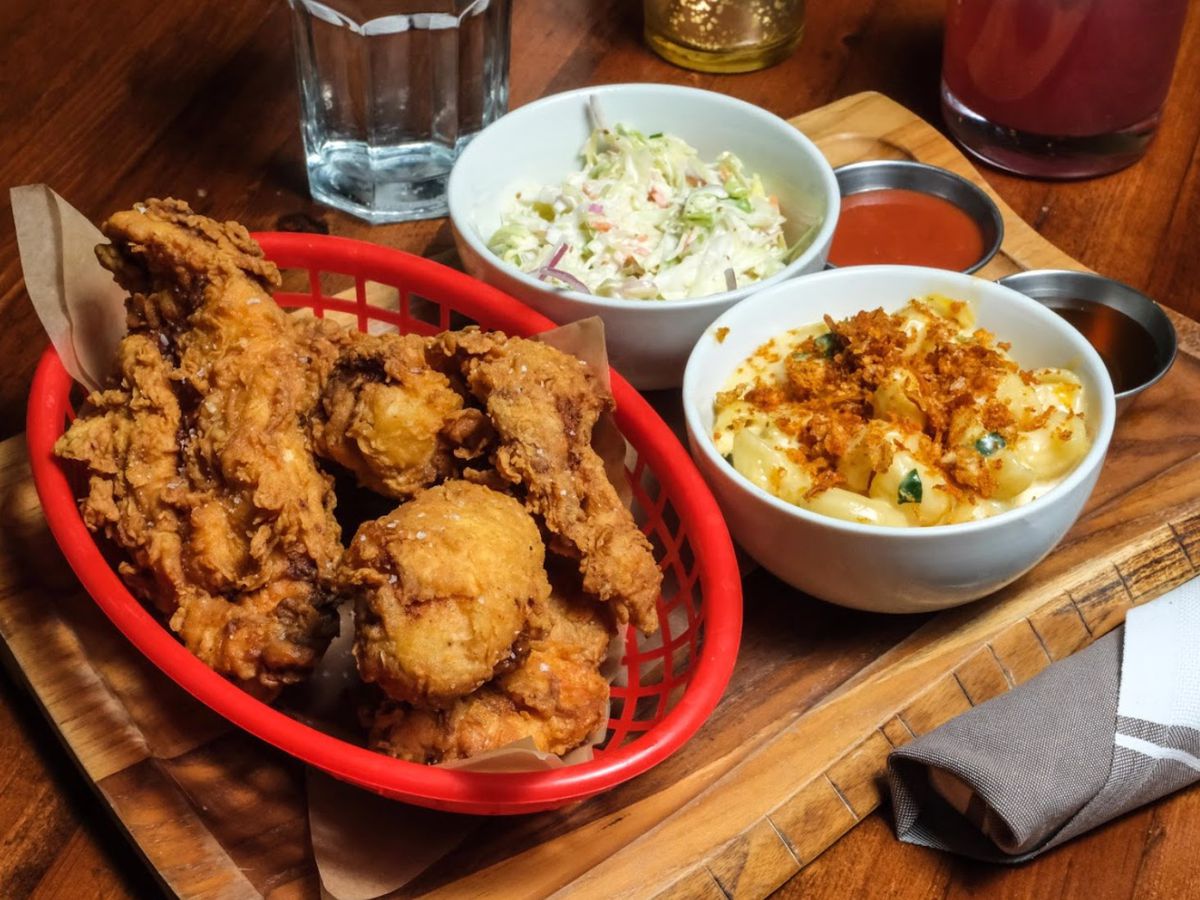 A basket of fried chicken next to a bowl of mac ânâ cheese and a bowl of cole slaw.