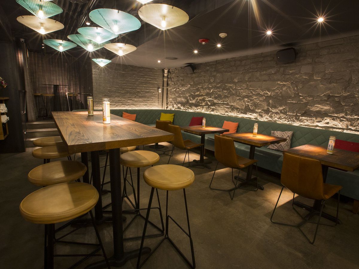 A dining room with white brick walls and teal banquettes.