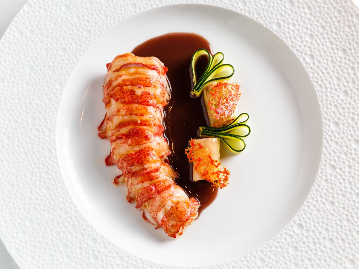 A speckled maine lobster tail accompanied by leek cannelloni and a rich dark brown red wine rosemary sauce