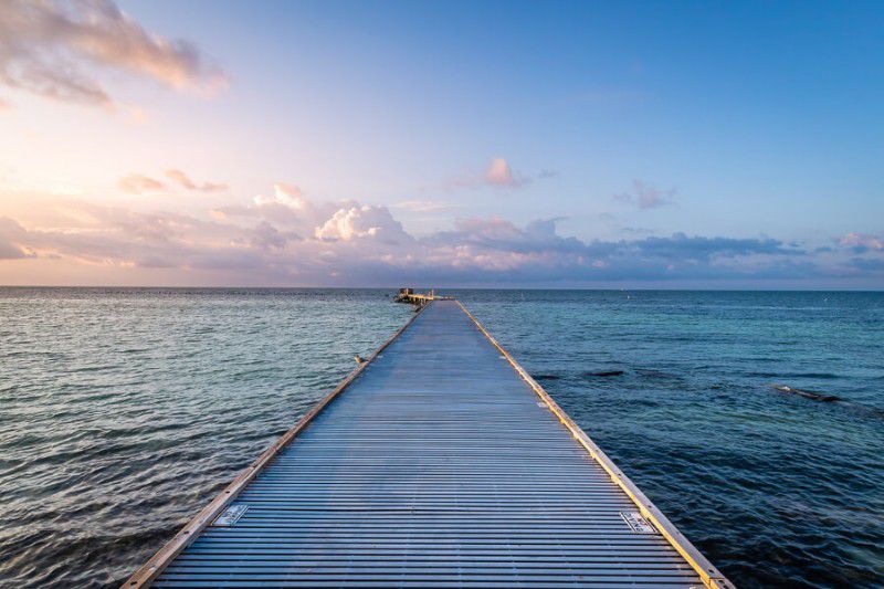 Wooden pontoon stretching out far into shallow water at twilight