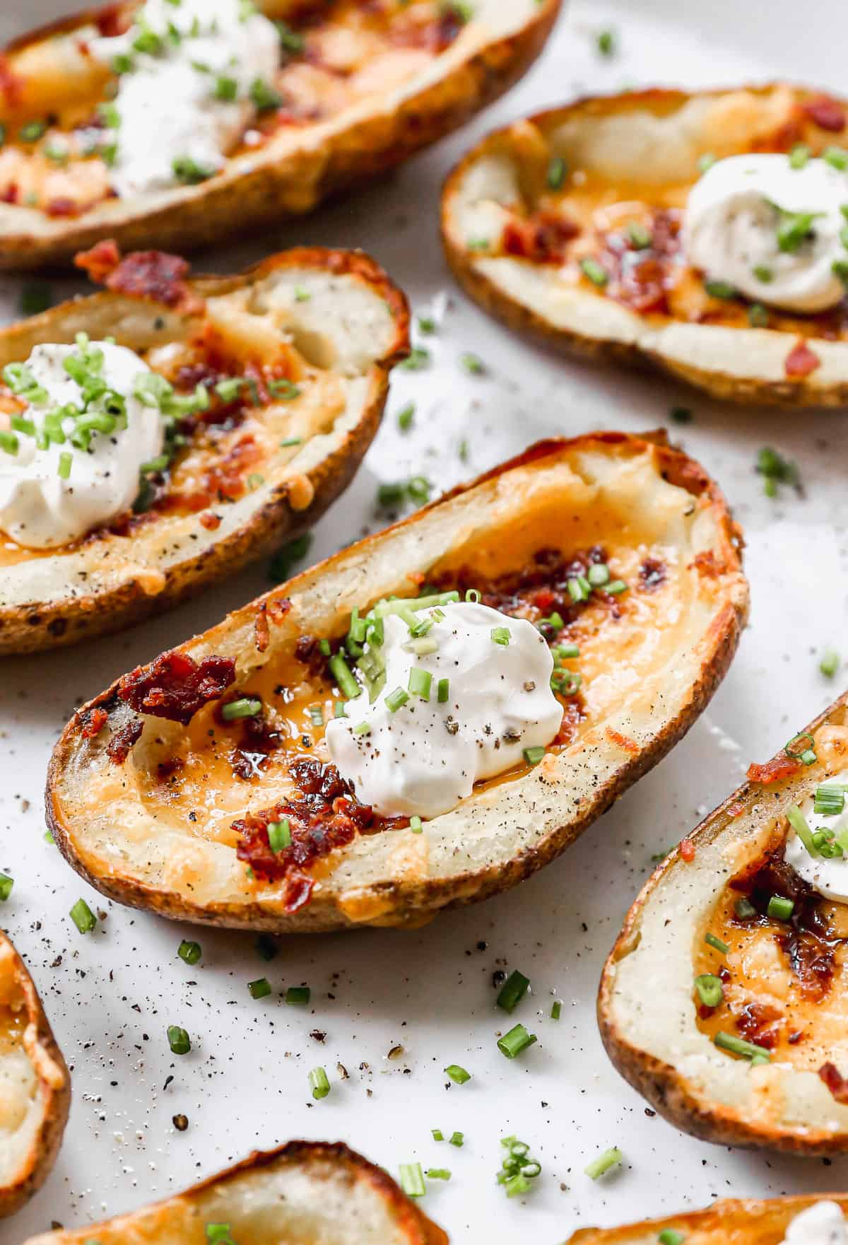 A close up image of the best loaded potato skins recipe topped with sour cream and chives.