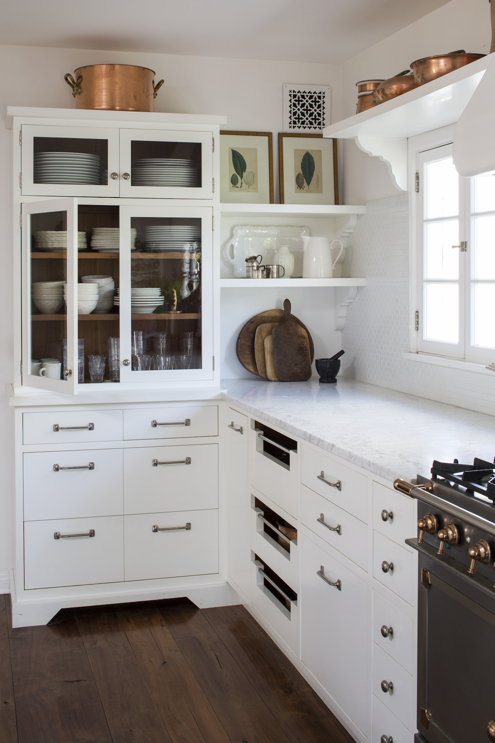 small white cottage kitchen with shelf above window and vintage window sash pulls uses as cabinet handles