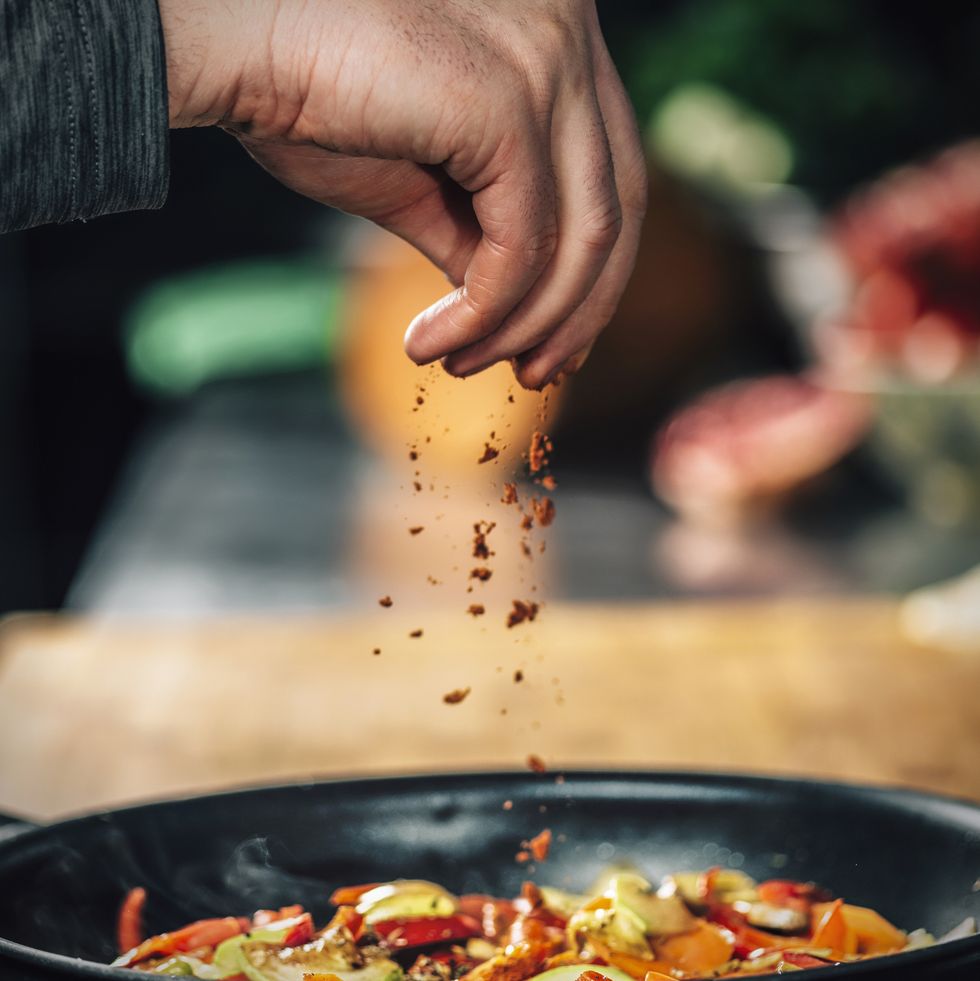 sprinkling ground red chili pepper paprika over sliced vegetables